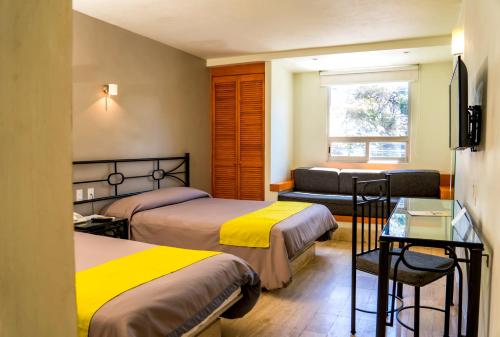 a hotel room with two beds and a couch at Hotel Arboledas Expo in Guadalajara
