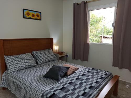 a bedroom with a bed with a pillow and a window at Apartamento 4 ótima localização Alumínio in Aluminio