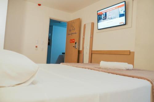 a bedroom with a bed and a tv on the wall at HUS Hotel MARINGA in Maringá