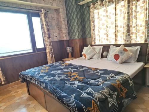 a bedroom with a bed with a blue comforter at Anand Niketan Homestay Shimla in Shimla