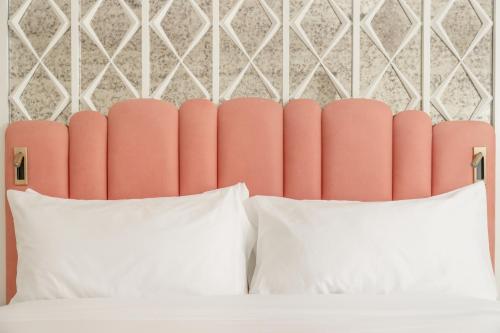 a bed with two white pillows and a pink headboard at Palm House Hotel Palm Beach in Palm Beach