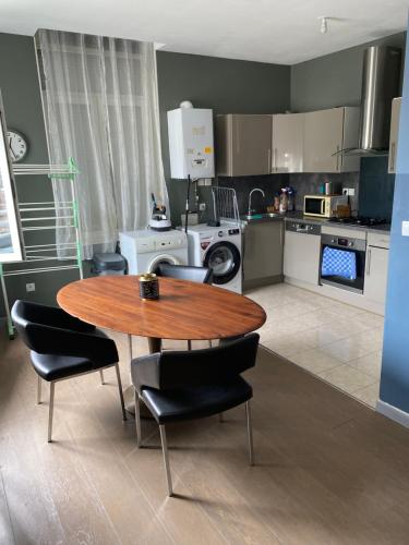 une cuisine avec une table en bois et des chaises noires dans l'établissement Appartement 2 chambre roubaix, à Roubaix