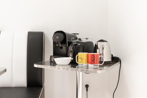 - une table avec des tasses à café et des appareils dans l'établissement Gaming flat à Toulouse centre avec parking gratuit, à Toulouse