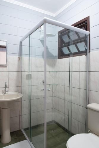 a bathroom with a glass shower with a toilet and a sink at Residencial Solar do Pescador in São Sebastião