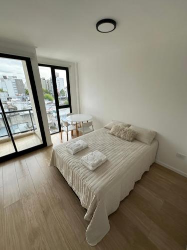 a white bedroom with a bed and a window at Departamento super luminoso - Zona 12 y 38 in La Plata