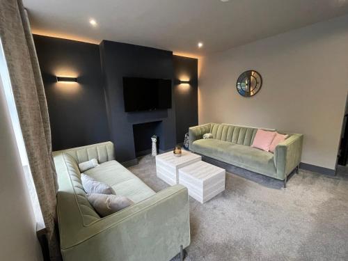 a living room with two couches and a tv at Cottage in Holmfirth Centre in Holmfirth