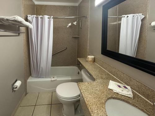 a bathroom with a toilet and a sink and a mirror at Motel 6 Buena Park, CA Anaheim Near Maingate Knotts in Buena Park