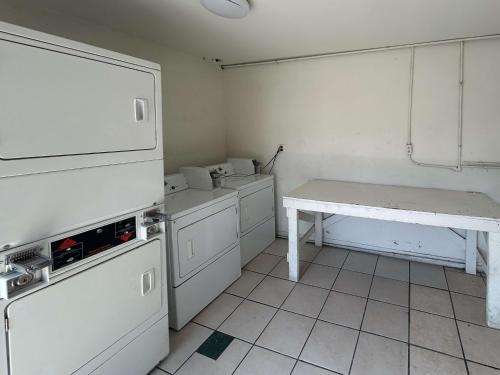 a kitchen with white appliances and a table in it at Motel 6 Buena Park, CA Anaheim Near Maingate Knotts in Buena Park
