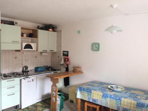 une cuisine avec des armoires blanches et une table à l'intérieur dans l'établissement Résidence Arzerier - Grand studio pour 4 personnes MAE-4674, à Montgenèvre
