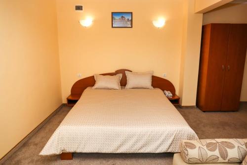 a bedroom with a large bed with white sheets at Hotel Bulgaria in Kŭrdzhali