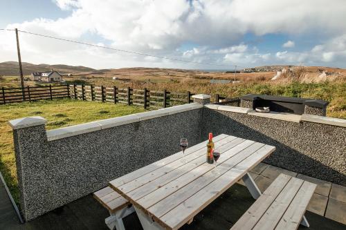 a picnic table with a bottle of wine on a wall at Carloway Self Catering, 5A Upper Carloway, Isle of Lewis, Outer Hebrides in Carloway