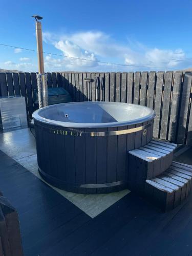 a blue tub sitting on a deck with a bench at Carloway Self Catering, 5A Upper Carloway, Isle of Lewis, Outer Hebrides in Carloway