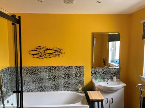 a bathroom with a tub and a sink and a mirror at Carloway Self Catering, 5A Upper Carloway, Isle of Lewis, Outer Hebrides in Carloway