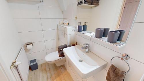 ein weißes Badezimmer mit Waschbecken und Toilette in der Unterkunft Ferienhaus Knippschild in Norderney