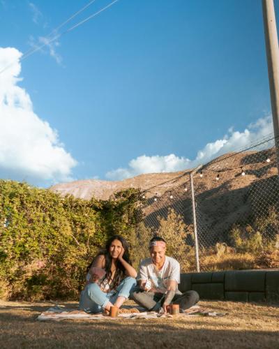 a man and a woman sitting next to a fence at Hana'q Hostel en el Valle sagrado, junto al rió Vilcanota in Urubamba