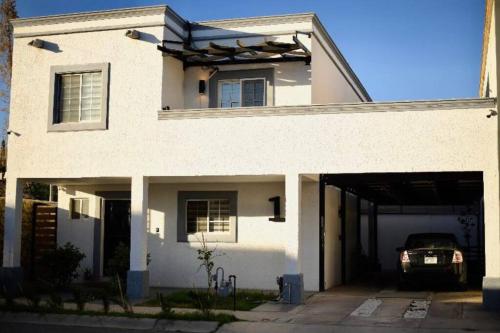 a white house with a garage with a car at Casa de lujo a 7min de consulado in Ciudad Juárez