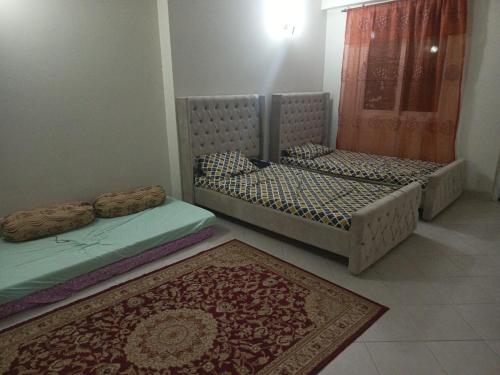 two beds in a room with a carpet and a rug at A house where you feel like home in Islamabad