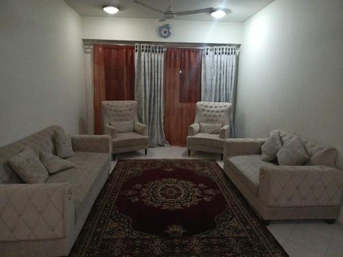 a living room with couches and chairs and a rug at A house where you feel like home in Islamabad