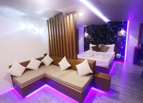 a room with two beds and a couch with purple lights at Ripple Beach Inn in Hulhumale