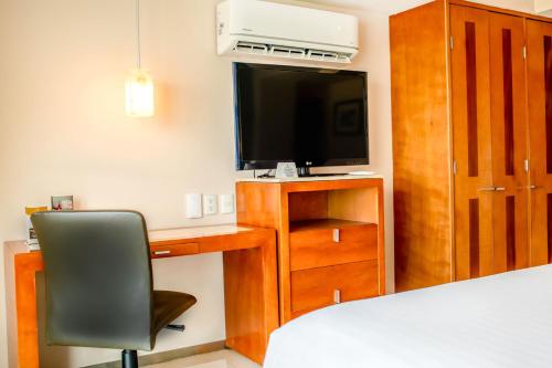 a bedroom with a desk with a television and a chair at Emporio Veracruz in Veracruz