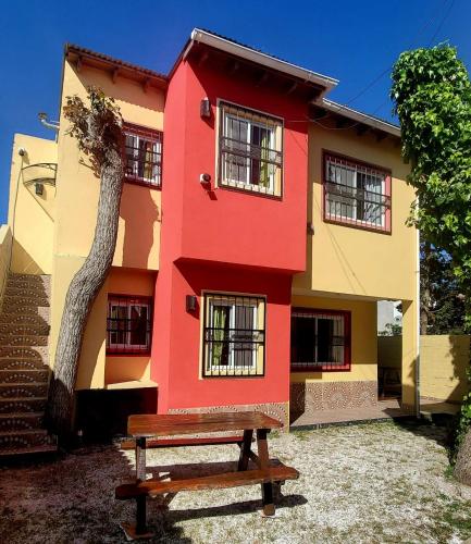 a red building with a bench in front of it at Arbolada Talas del Tuyu in San Clemente del Tuyú