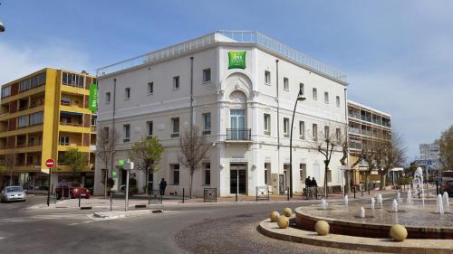 a white building with a fountain in front of it at Ibis Styles Hyères Rooftop & Spa in Hyères