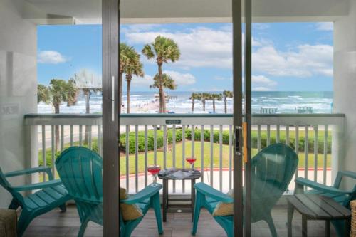 a balcony with chairs and a table with a view of the beach at Turtley Awesome Beachfront Condo Pool in Galveston