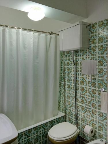 a bathroom with a shower curtain and a toilet at Caparica for Rent in Costa da Caparica
