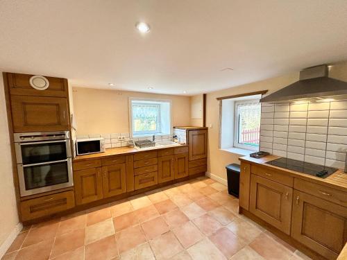 a large kitchen with wooden cabinets and a sink at Chalet des roches - Plainfaing in Plainfaing