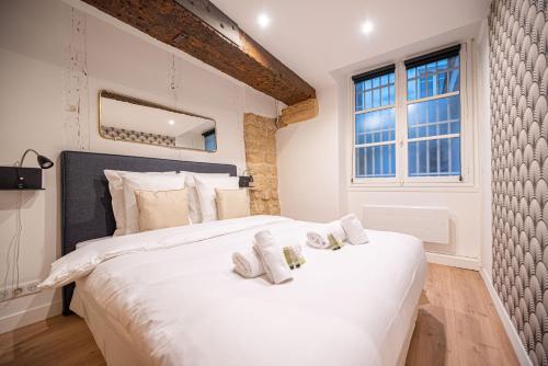 une chambre avec un grand lit blanc avec des serviettes dessus dans l'établissement Beautiful Apartment in Saint Germain, à Paris
