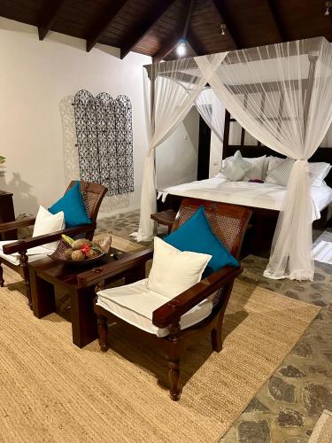 a room with two beds with chairs and a table at Firefly Estate Bequia in Crescent Beach
