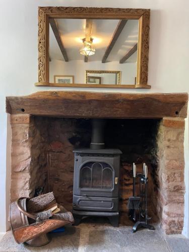 a fireplace with a mirror and a wood stove at The Linhay in Minehead