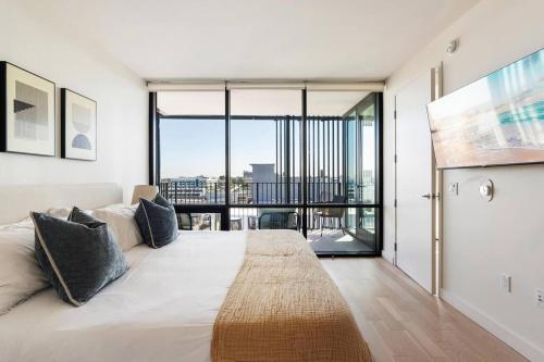 a bedroom with a large white bed with a large window at The Rose Quartz - Rooftop Pool, Gym Glamorous Santa Monica 2BR in Los Angeles