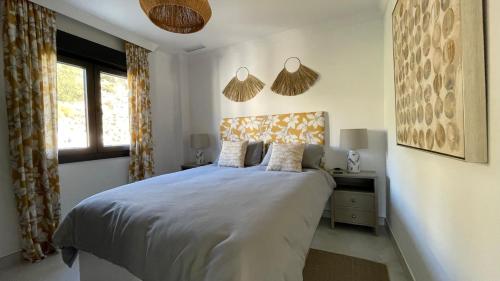 ein weißes Schlafzimmer mit einem Bett und einem Fenster in der Unterkunft Comino Penthouse in Cómpeta