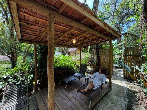 a woman sitting on a pergola on a wooden deck at Pousada Olho D'Água in Visconde De Maua