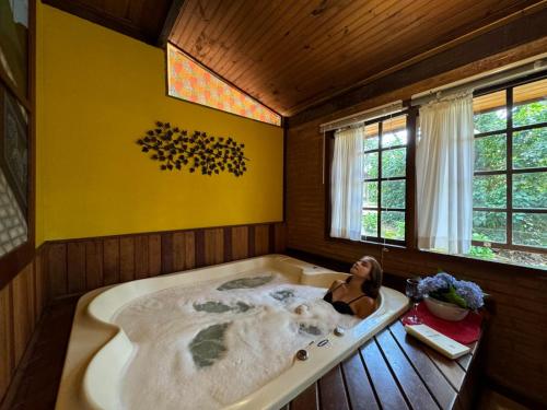 a woman laying in a bath tub in a room at Pousada Olho D'Água in Visconde De Maua