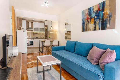 a living room with a blue couch and a kitchen at Harizma apartmani in Kragujevac