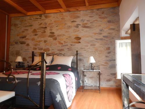 a bedroom with a bed and a stone wall at Casa da Pracica, Serapicos in Vale de Frades