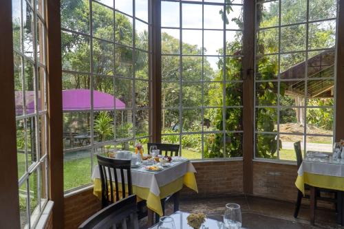 a restaurant with large windows and tables and chairs at Pousada Olho D'Água in Visconde De Maua