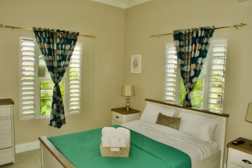 a bedroom with a bed and two windows at Paradise in Edgehill, Jamaica! in St Mary