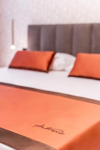 a bed with orange pillows on top of it at Ambrosia Room & Apartment in Rossano