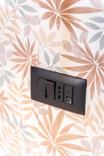 a digital clock on a wall with floral wallpaper at Ambrosia Room & Apartment in Rossano