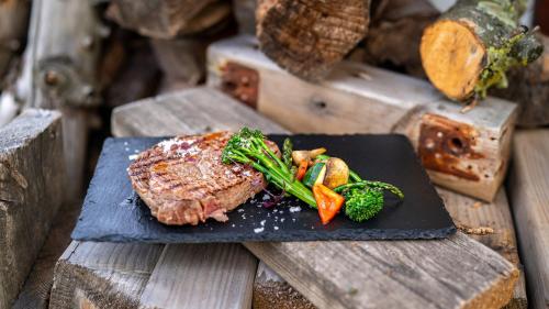 a steak with broccoli on a black plate on a wooden table at Holiday Inn Berlin Airport - Conference Centre by IHG in Schönefeld