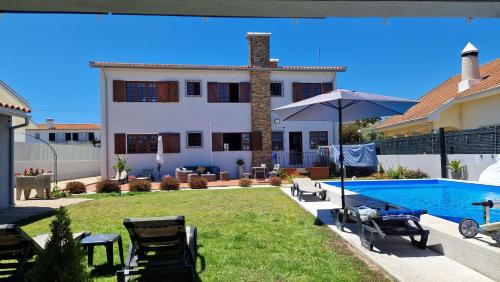 a villa with a swimming pool and a house at Beachwalk guesthouse in Esmoriz