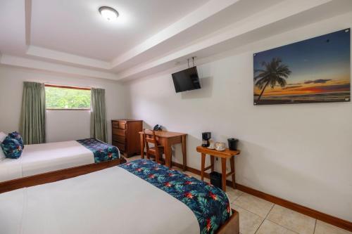 a hotel room with two beds and a television at Jaco Laguna Resort & Beach Club in Jacó