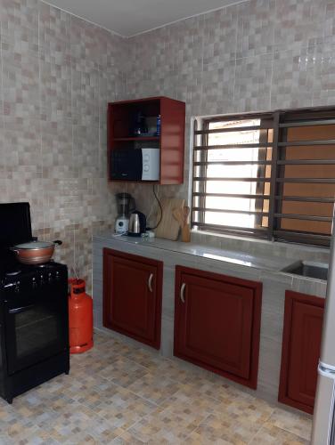 a kitchen with red cabinets and a black stove at Magnifique Maison de ville Bord de mer Cotonou Fidrjossè in Cotonou