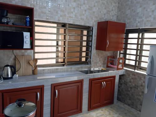 a kitchen with brown cabinets and a sink and a refrigerator at Magnifique Maison de ville Bord de mer Cotonou Fidrjossè in Cotonou