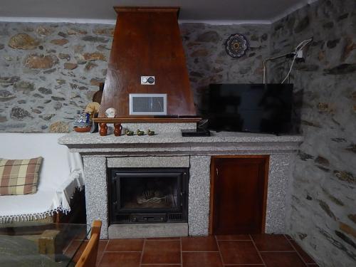 a living room with a fireplace and a flat screen tv at Casa da Pracica, Serapicos in Vale de Frades