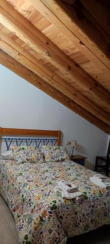 a bed in a bedroom with a wooden ceiling at ALTOGREDOS Hotel Rural y apartamentos turísticos in Hoyos del Espino