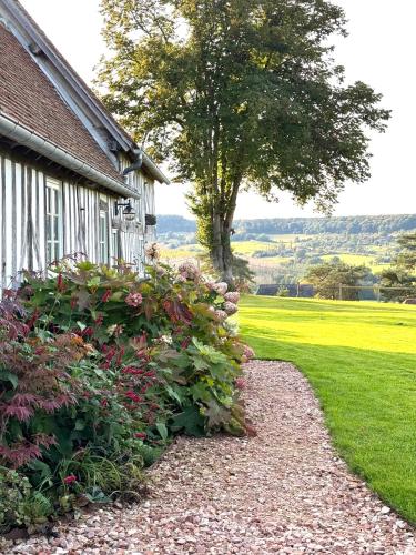 a garden path next to a house with a tree at Le Cottage enchanteur du Renouard avec sa Vue panoramique in Le Renouard